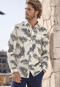 Korte mouwen, overhemd met knoopsluiting in licht beige met een zwart palmenprint. Heeft een enkel borstzakje en een zachte, gestructureerde stof.