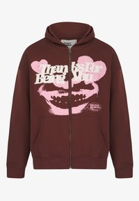 Bordeauxfarbene Zip-Hoodie mit weißen und pinken Grafiken, einem Lächel-Design und zwei Vordertaschen. Weicher Stoff mit lockerer Passform.