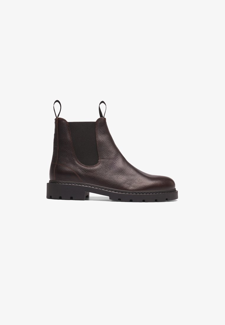 Bota Chelsea de couro castanho com painéis laterais elásticos, acabamento texturizado e sola de borracha preta resistente com entalhes para aderência.