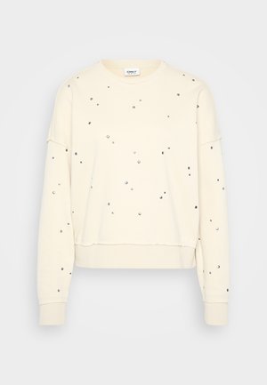 Cream sweatshirt with a round neck, long sleeves, and scattered silver studs. Soft texture and relaxed fit with ribbed cuffs and hem.