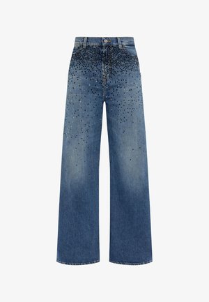 Jean en denim bleu à jambe large avec une finition délavée. Présente des ornements de clous noirs et argentés concentrés en haut.