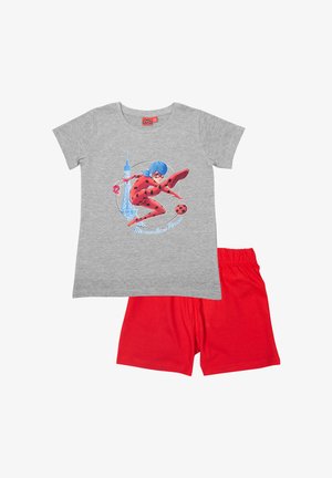 T-shirt in cotone grigio con una grafica di un personaggio in costume rosso che calcia un pallone nero, abbinata a pantaloni corti in cotone rossi.