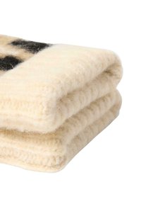 Uldtæppe flettet, med en cremet hvid farve og en blød, fluffy tekstur samt et subtilt sort mønster i den ene kant.