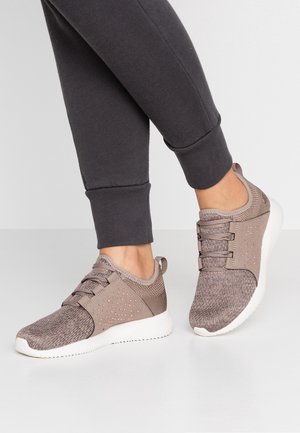Lekkoatletyczne buty w jasnobrązowym kolorze z teksturowaną dzianinową cholewką, perforowanymi detalami i białą gumową podeszwą.