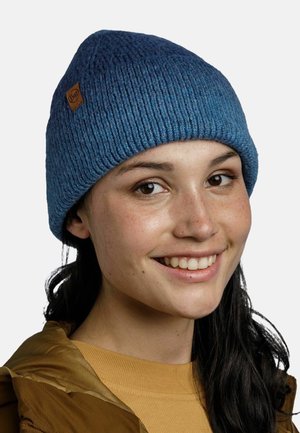 Gorro de punto azul con textura acanalada, que presenta un parche de cuero marrón con el logo. El sombrero tiene una forma redondeada y un ajuste ceñido.