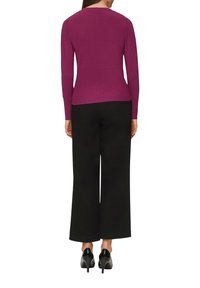 Maglione aderente viola a maglia con maniche lunghe, scollatura rotonda e texture liscia, abbinato a pantaloni neri a gamba larga e tacchi neri.