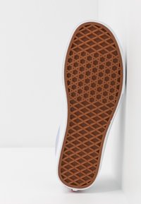 Suela de zapatilla de goma, presenta un patrón hexagonal texturizado en marrón, paredes laterales blancas y un diseño minimalista.
