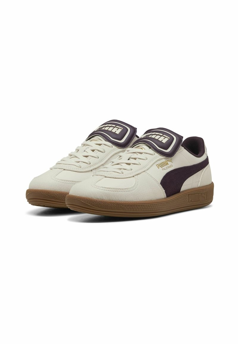 Baskets Puma avec un dessus en synthétique crème, semelle en caoutchouc marron, bande latérale violet foncé et languette rembourrée avec logo. Design à lacets.