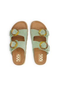 Green suede slide sandals with two circular amber accents, a cushioned brown insole, and a lightweight white sole. Checkered label inside.