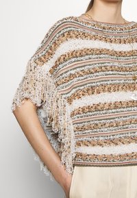 Fransengrauer Poncho mit horizontalen Streifen in erdigen Tönen von Orange, Grün und Weiß. Hergestellt aus strukturiertem Stoff mit lockerer Passform.