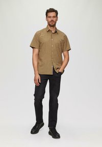 Korte mouwen, geruit overhemd in bruin en beige, met knoopsluiting. Gecombineerd met donkere jeans en zwarte sneakers. Eenvoudige, casual stijl.