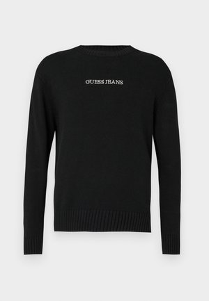 Maglione nero con maniche lunghe, orlo e polsini a coste, con la scritta "GUESS JEANS" ricamata in bianco sul davanti. Tessuto in maglia morbida.