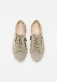 Baskets en suede gris avec un laçage sur le devant, des zips latéraux et une semelle en caoutchouc. L'intérieur présente un logo imprimé sous une doublure lisse.