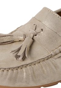 Beige mokasyn zamszowy z teksturowym wykończeniem, z dekoracyjną frędzelkiem i haftowanymi detalami na górze oraz podeszwie.