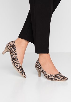 Chaussures à talons hauts en imprimé léopard avec un bout pointu, en tissu doux, et un talon en bois texturé de 3 pouces. Portées avec un pantalon noir ajusté.