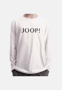 Valkoinen pitkähihainen t-paita, jossa on musta "JOOP!" -logo rinnassa. Valmistettu pehmeästä kankaasta, jossa on pyöreä kaula-aukko ja rento istuvuus.