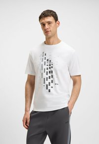 White short-sleeve T-shirt featuring a geometric graphic design in gray tones, with the brand name "BOSS" printed near the bottom.
