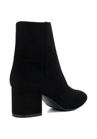 Black suede ankle boot with a rounded toe, a curved shaft, and a chunky heel. The texture is soft and the design is seamless with no visible fasteners.