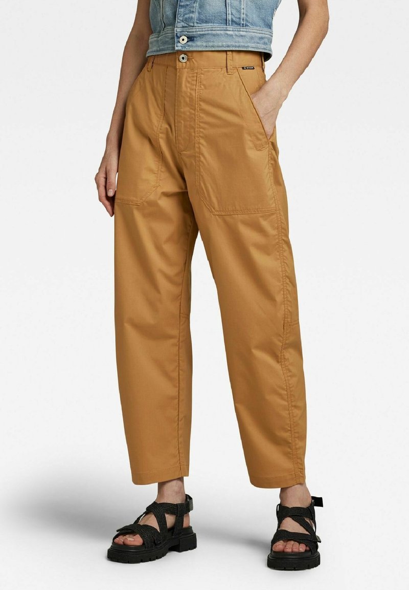 Pantalons cargo beiges à taille haute avec poches latérales et coupe décontractée. Fabriqués en tissu durable, avec une fermeture à bouton et des jambes larges.