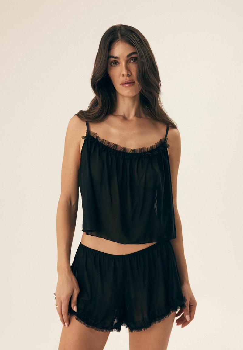 Czarny, przezroczysty dwuczęściowy zestaw do relaksu, składający się z krótkiego topu z falbanami oraz dopasowanych szortów z elastycznym pasem i falbaniastym wykończeniem.