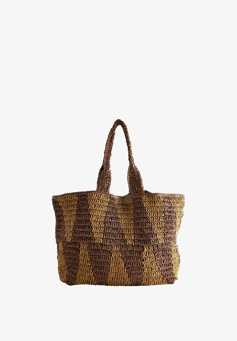Sac cabas en paille tissée avec de longues poignées, arborant un motif en zigzag marron et beige, placé debout sur un fond blanc.