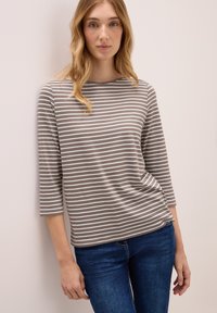 Gestreiftes Langarmoberteil in Hellgrau und Weiß, mit einem Bootsausschnitt, weichem Textil und lässigem Schnitt. Die Trägerin kombiniert es mit Jeans.