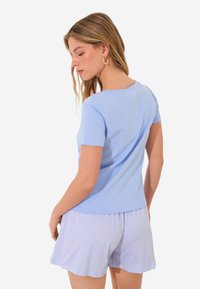 Ljust blå t-shirt med kort ärm och rund halsringning, gjord av ett mjukt tyg, i kombination med ljusrandiga shorts. Mjuk struktur, avslappnad passform.