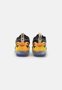 Schwarze und graue Sportschuhe mit bunten Akzenten, die eine transparente Sohle und eine auffällige "LOCK"-Markierung an der Ferse aufweisen.