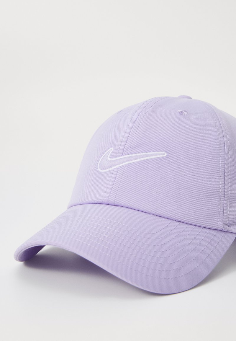 Gorra de algodón morada con visera curvada, que presenta un logotipo de Nike bordado en blanco en la parte frontal. Textura suave y diseño estructurado.