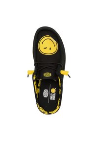 Scarpa nera in tela con un grande sorriso giallo sulla parte superiore, con accenti gialli e una fodera interna a fantasia.
