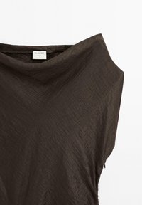 Brun, rynket stofoverdel med et løst design. Har vid halsudskæring og minimalistisk mærke. Blød tekstur med en let glans.