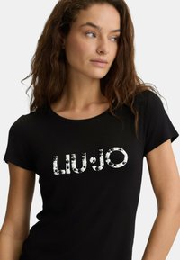 T-shirt nero a maniche corte con un audace logo "LIU·JO" adornato da dettagli in bianco e nero e scollo rotondo.