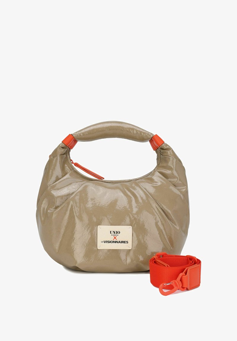 Sac à main beige brillant à forme arrondie, doté d'une anse orange en accent, d'une fermeture éclair et d'une sangle orange détachable. Patch logo visible.