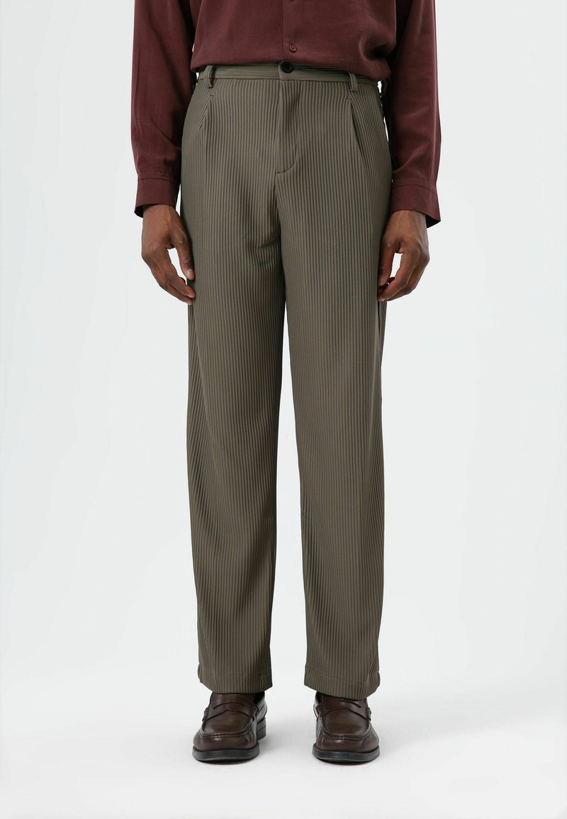 Olive green pinstriped trousers with a loose fit, featuring front pleats and side pockets, paired with brown loafers.