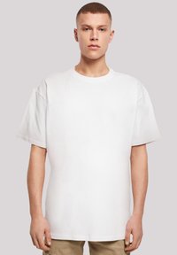 Bílý oversized tričko s kulatým výstřihem a krátkými rukávy, vyrobené z měkké bavlny. Jednoduchý design, bez viditelných vzorů nebo akcentů.