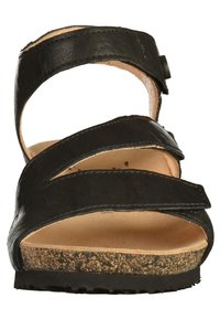 Sandale en cuir noir avec plusieurs lanières entrecroisées, boucle ajustable, semelle en liège et semelle en caoutchouc texturé. Design à bout ouvert.