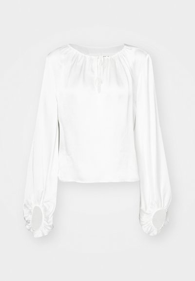 Blouse blanche à manches longues en tissu lisse, avec un col froncé, des détails à cordon et des poignets élastiques avec des ouvertures rondes.