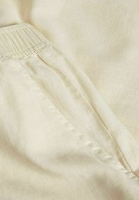 Telaje color crema con una textura suave, que presenta una cintura elástica y costuras cosidas, enfatiza un diseño ligero y transpirable.