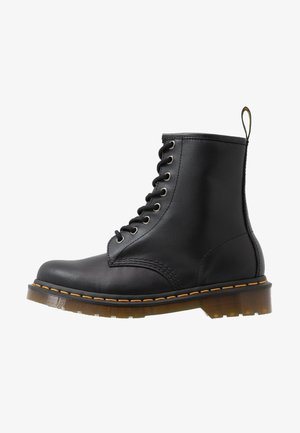Stivaletto nero in pelle con lacci, suola spessa traslucida e cuciture gialle lungo il bordo, con linguetta posteriore.