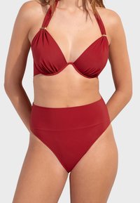 Crveni bikinis set koji ima halter vrat dizajn, trokutaste košarice i donji dio s visokim strukom. Glatka tekstura s zlatnim detaljima.