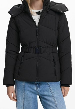 Mustapintainen toppatakki hupulla, etuvetoketju, vyö vyötäröllä, vetoketjulliset sivutaskut, päällä vaaleansiniset farkut.