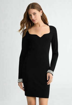 Abito lungo nero con maniche a lungo, scollatura rotonda e silhouette aderente. Accenti decorativi in strass ai polsini. Tessuto morbido, lunghezza fino al ginocchio.