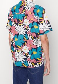 Short-sleeve shirt featuring a navy background with vibrant floral patterns in pink, blue, and yellow. Made of lightweight fabric.