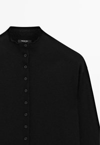 Black button-up cardigan sweater with a soft texture, ribbed collar, and eight black buttons along the front. Label visible inside the neck.