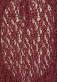 Tissu en dentelle bordeaux avec un motif floral et un fond transparent, doté d'une couture verticale et d'un détail de fermeture éclair centrale.