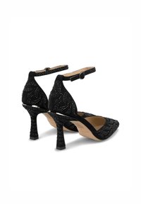 Scarpe nere in suede con tacchi alti, decorate con cristalli, punta affusolata, cinturino alla caviglia e design del tacco testurizzato.