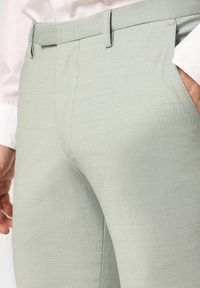 Lichtgrijze broek, getailleerde pasvorm, gestructureerde stof met een subtiel patroon, met rechte pijpen en riemlussen.