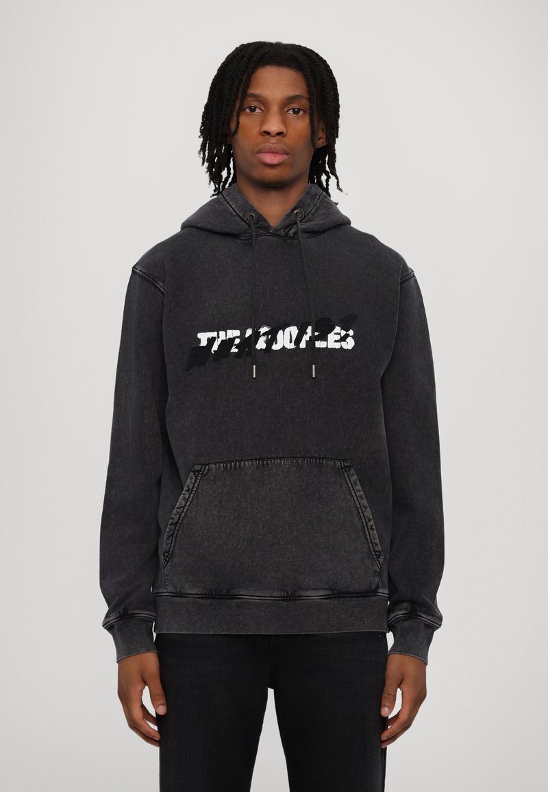 Black denim hoodie with a front kangaroo pocket, featuring a distressed white text graphic. It has a drawstring hood and ribbed cuffs.