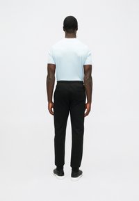 Gaiši zils īsām piedurknēm T-krekls ar apaļu kakla izgriezumu, kombinēts ar melniem šauriem biksēm, kas izceļ gludu tekstūru un minimālu dekoru. Iekļautas melnas kurpes.