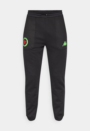 Pantaloni de trening negri cu talie elastică, având accente de logo verde și roșu pe buzunare și un design cu picioare conice.